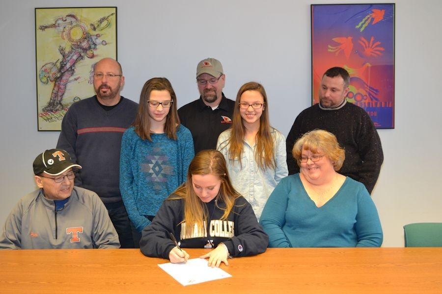 Anna signs her letter of intent as her family, coaches and TAHS principal and athletic director look on