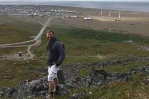 Courtland Pannebaker with the village of Gambell and the Bering Sea in the background.