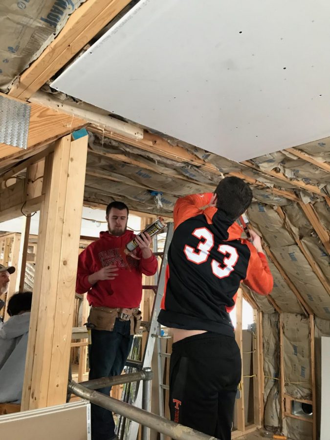 Seniors Cory Lehman and Carter Maceno apply adhesive before installing the drywall on the ceiling.  The house got framed, insulated and drywalled this year.  