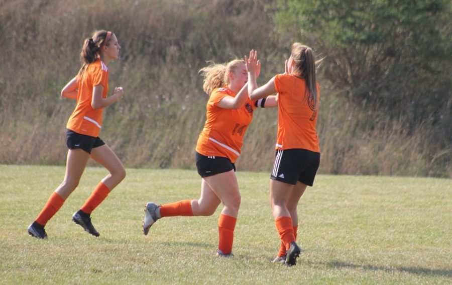 Kendall Markley, Chloe LaRosa, and Sophia Nelson celebrating after a goal.