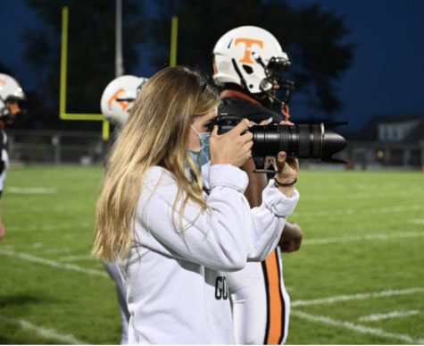 Lucia pointing her camera to the field to capture a play during a TAHS football game