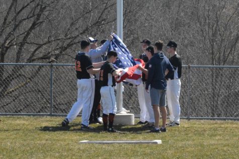 TAHS senior baseball players raise the flag at the flagpole honoring their friend and teammate Adam Fink.