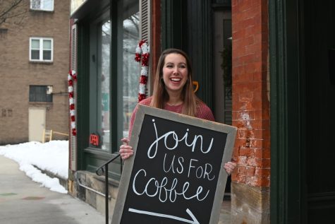 Shannon Rice in front of the business with a sign that says "join us for coffee."