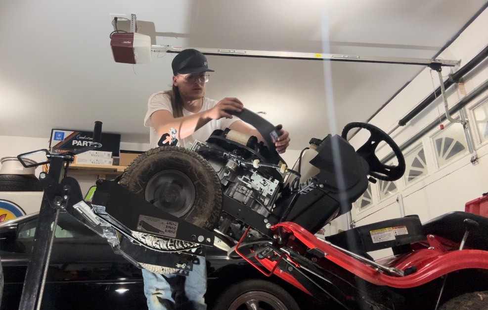 Thompson at work in his shop on an engine swap in a Craftsman riding mower. See video posted at the bottom of the story. (photo courtesy of Alex Thompson).