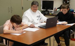 TAMS Paraprofessional Peggy Cox working with two of her sixth grade students.