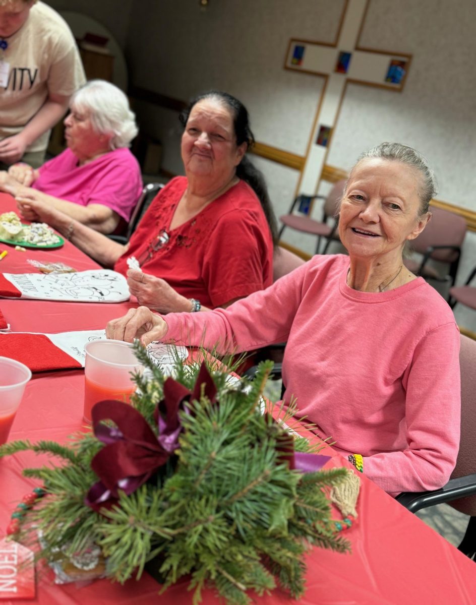 Residents at Cedarwood Rehabilitation and Healthcare Center during their annual Holiday Party with floral arrangements created by the participants  